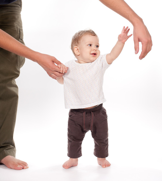 Baby macht erste Schritte mit Hilfe des Vaters auf weiß - Foto, Bild