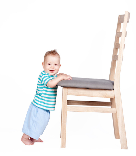 bambino in piedi contro una sedia isolata su bianco
 - Foto, immagini