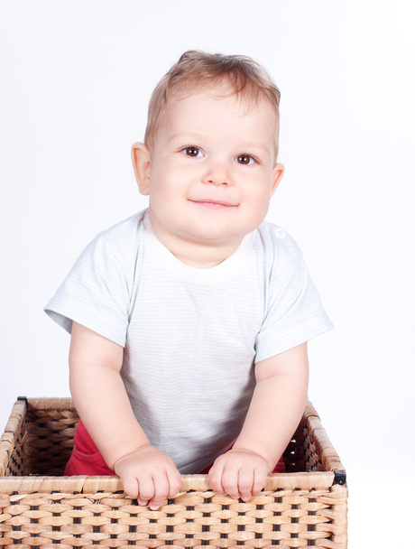 Мальчик в плетеной корзине на белом
 - Фото, изображение