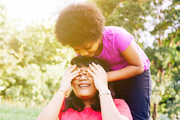 Kid covering mother's eyes in the green park with copy space - Daughter and mother relationship - Foto, immagini