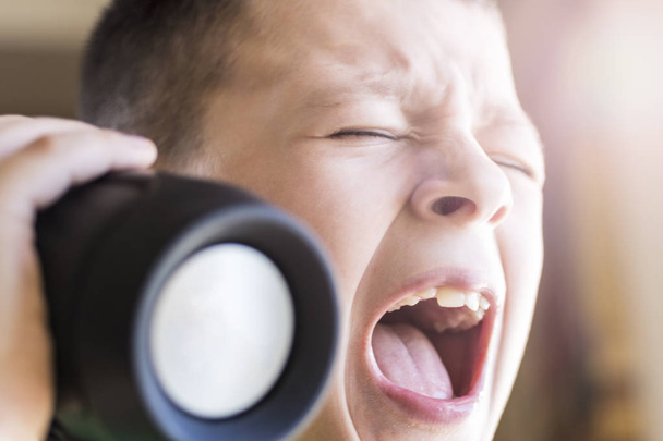 Young Boy Singing Out Loud tout en écoutant de la musique sur haut-parleur sans fil. Visage expressif
. - Photo, image