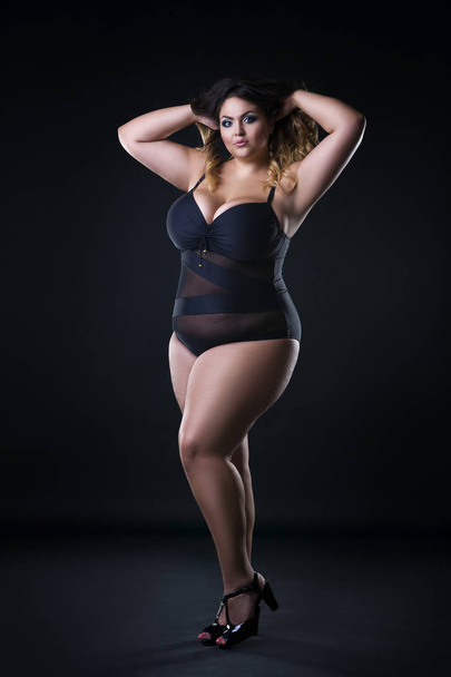 Young beautiful caucasian plus size model in swimsuit, xxl woman on black background - Zdjęcie, obraz