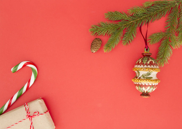 Cornice natalizia su sfondo rosso. Rami di abete verde, regali di Natale, decorazioni e bastoncini di zucchero. Vista dall'alto, posizione piatta. Copia spazio per testo
 - Foto, immagini