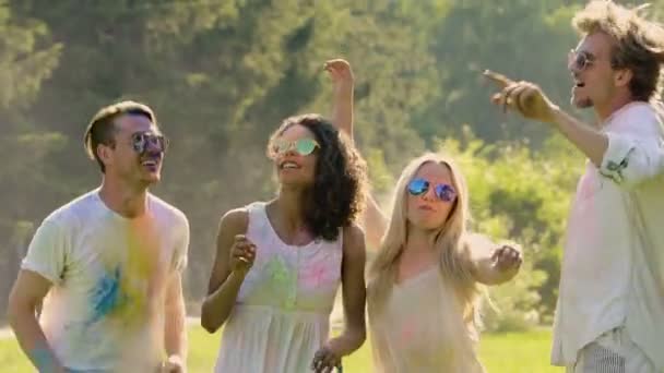 Amigos felizes cobertos de cores holi pulando e rindo, desfrutando do festival
 - Filmagem, Vídeo