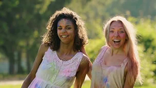 Hermosas amigas cubiertas de coloridos abrazos de pintura, sonriendo a la cámara
 - Imágenes, Vídeo