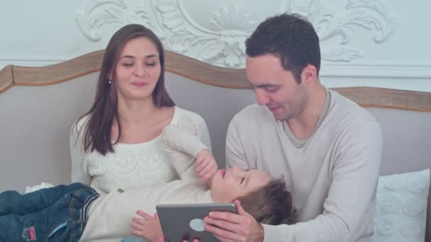 Šťastná rodina hrát s jejich syn sedí na gauči při používání digitálních tablet - Záběry, video