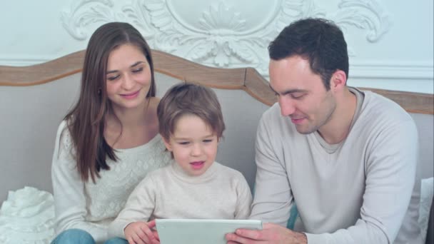 Счастливая семья и сын смотрят планшет на диване
 - Кадры, видео