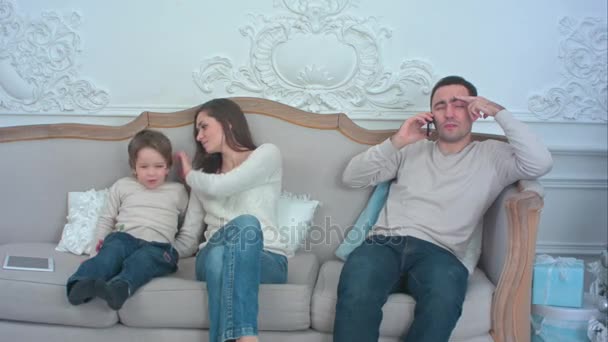 Cansado padre hablando por teléfono mientras la madre está jugando con su lindo niño
 - Imágenes, Vídeo