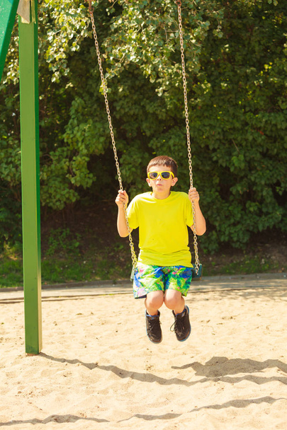 Boy playing swinging by swing-set. - Photo, image