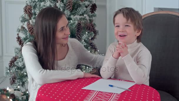 A happy boy and his mother fantasizing what to write in a letter to Santa - Imágenes, Vídeo