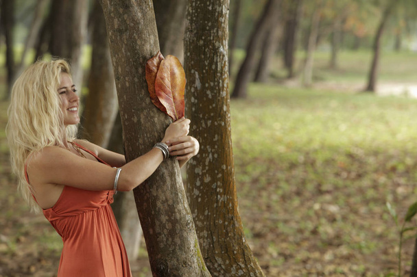 blonde woman holding tree - Foto, afbeelding