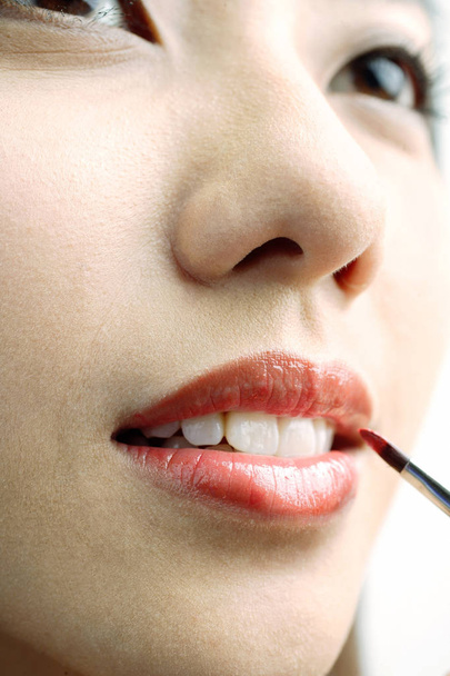 Woman putting on lipstick - Fotoğraf, Görsel