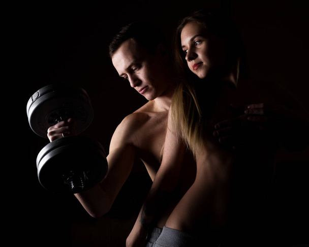 beautiful young sporty sexy couple showing muscle on a dark background - Foto, afbeelding