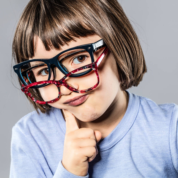 thinking cheeky little kid trying many eyeglasses hesitating for choice - Photo, Image