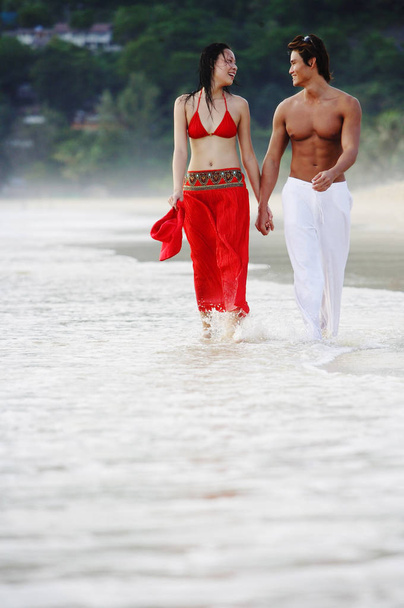 Couple walking along beach - Φωτογραφία, εικόνα