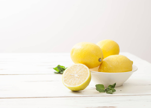 lemons and mint on white wooden table - Фото, изображение
