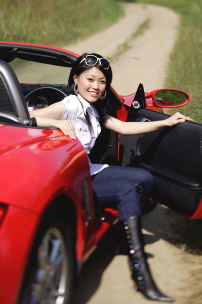 Frau steigt aus rotem Sportwagen aus - Foto, Bild