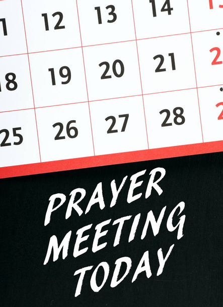 The words Prayer Meeting Today in white text on a blackboard underneath a wall calendar as a reminder - Photo, Image