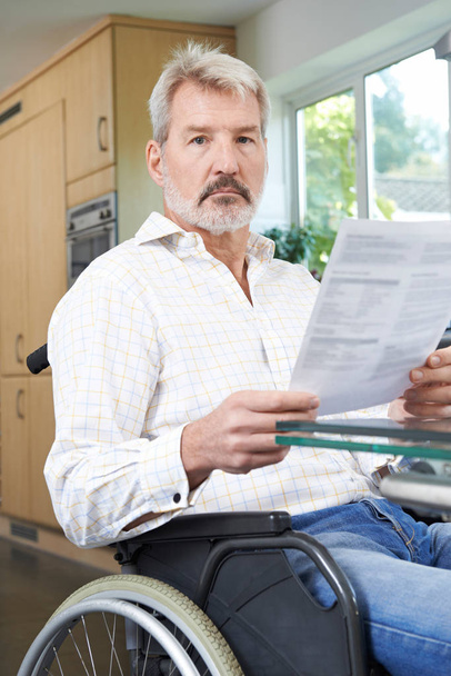 Frustrated Man In Wheelchair Reading Letter - Foto, Bild