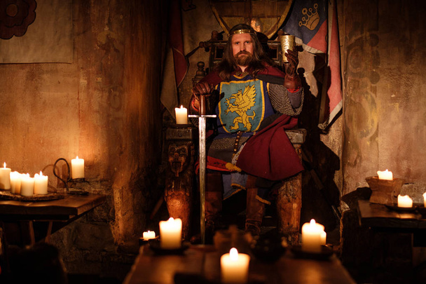 Middeleeuwse koning op de troon in oude kasteel-interieur. - Foto, afbeelding