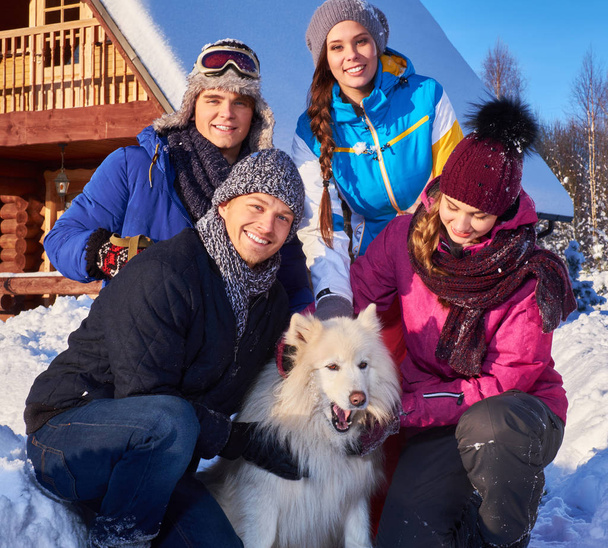 Los amigos alegres con el perro pasan las vacaciones de invierno juntos en la casa de campo de montaña
 - Foto, Imagen