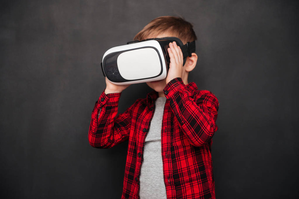 Niño usando y sosteniendo dispositivo de realidad virtual sobre pizarra
 - Foto, imagen