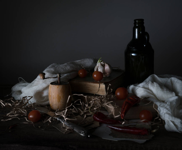 still life, vintage. cherry tomatoes, old bottle with the oil mill and the  silver knife on a wooden table. - Foto, Imagem