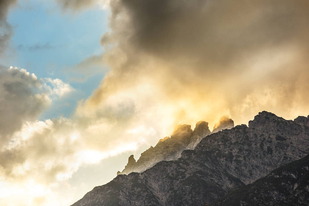 Montagnes sommets de pierre avec des nuages orange sous la lumière du coucher du soleil
. - Photo, image