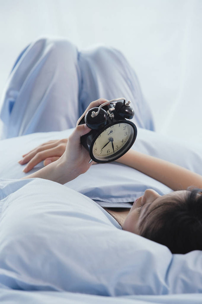 womanlooking at alarm clock - Zdjęcie, obraz
