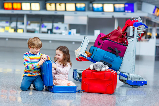 Two little kids, boy and girl going on vacations trip with suitcase at airport - Foto, immagini