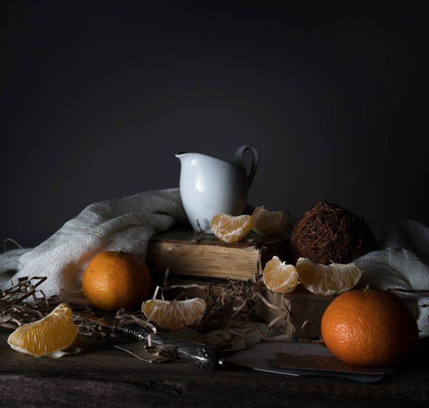 still life, vintage. tangerines, tangerine slices, milk, scarf and old silver knife on a wooden table. - Zdjęcie, obraz