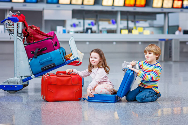 Kaksi pientä lasta, poika ja tyttö lähdössä lomalle matkalaukku lentokentällä
 - Valokuva, kuva