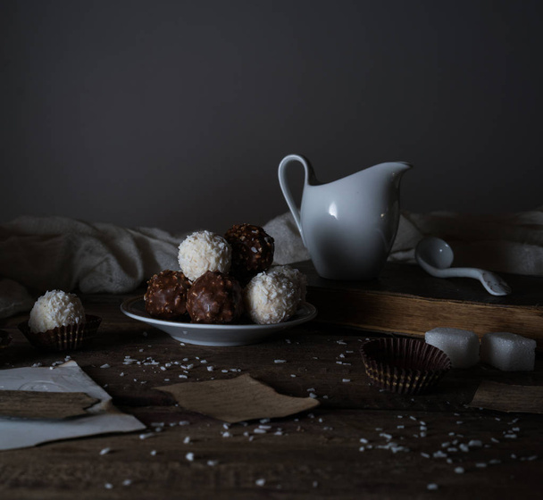 still life, vintage. candy, drapery, a milkman,  letter on the wooden table. black background - 写真・画像