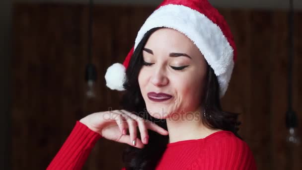 Beautiful and Charming Girl Santa Claus For Christmas. She Smiles Looking at the Camera. it is Funny, Charismatic and Attractive. New Year. - Materiaali, video