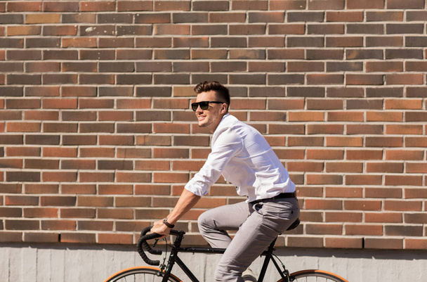 young man riding bicycle on city street - Fotoğraf, Görsel