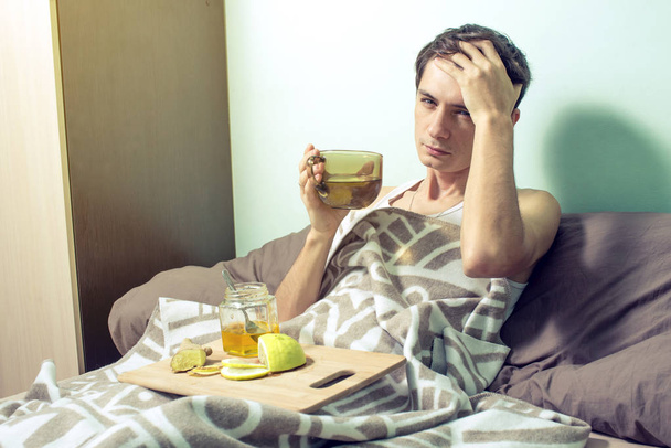 νεαρός άνδρας βρίσκεται στο κρεβάτι άρρωστη με κρυολόγημα και τη γρίπη - Φωτογραφία, εικόνα