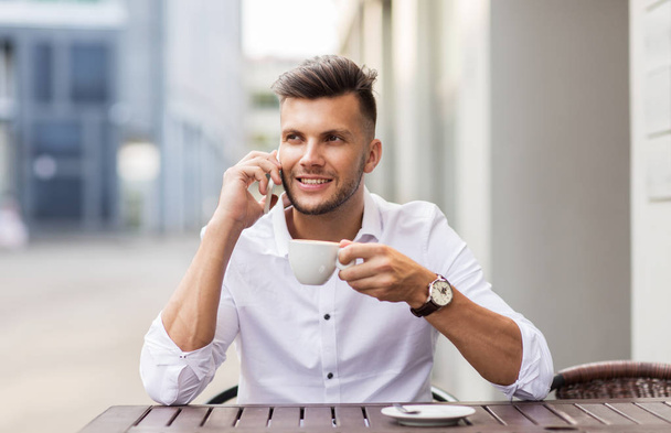Mann mit Kaffee telefoniert mit Smartphone im Stadtcafé - Foto, Bild