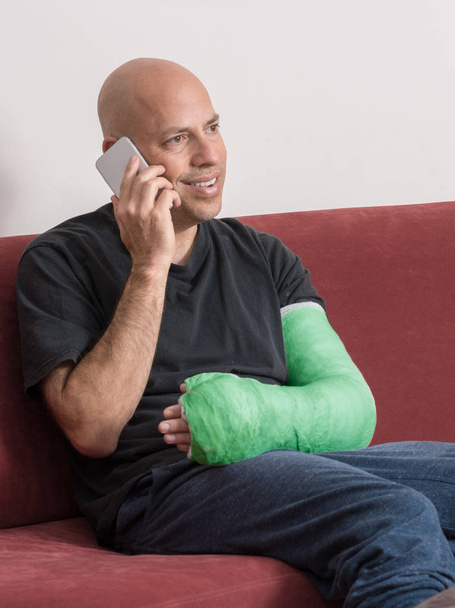 Young man with an arm cast talking on his phone - Photo, Image