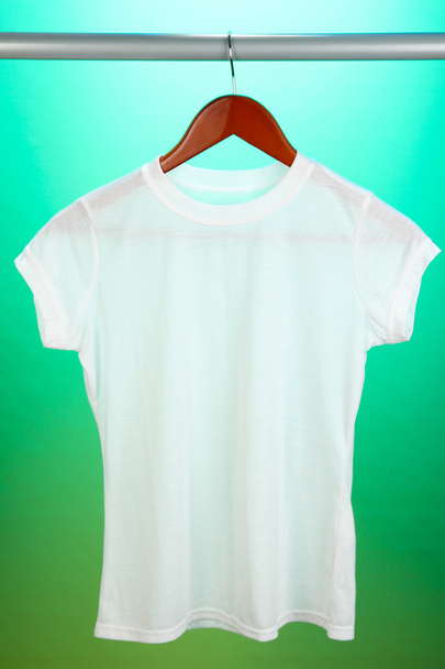 White t-shirt on hanger on green background - Zdjęcie, obraz