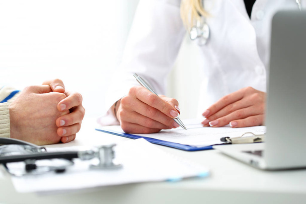 Ärztin hält silbernen Stift in der Hand, der Patientenanamnese füllt - Foto, Bild