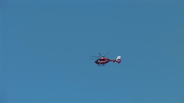 κόκκινο ελικόπτερο που πετά στον γαλάζιο ουρανό - Πλάνα, βίντεο
