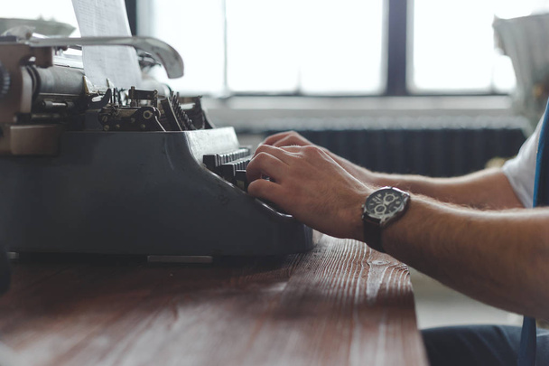 Hombre trabajando en máquina de escribir retro en el escritorio en la sala de estar
 - Foto, imagen