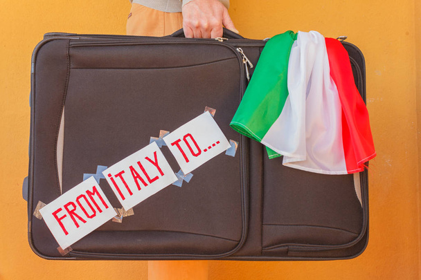uma pessoa tem uma mala na mão para emigrar da Itália
 - Foto, Imagem