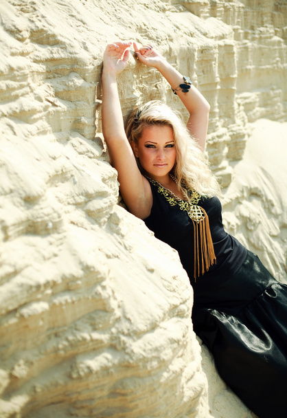 Fashion blond girl in long black dress posing in sand desert with hands up - Φωτογραφία, εικόνα