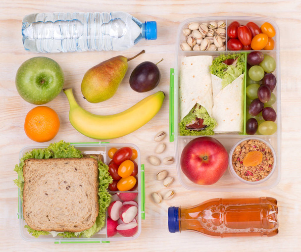 Food for lunch, lunchboxes with sandwiches, fruits, vegetables, and drinks - Photo, Image