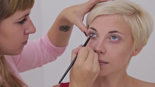 Professional make-up artist applying eyeliner around the entire eye of model - Footage, Video