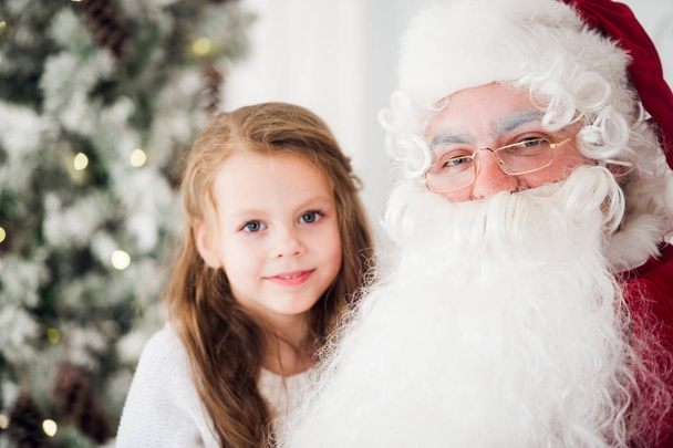 little girl talking with an old santa claus - Foto, Bild