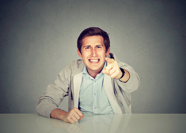 Angry man sitting at table screaming pointing with finger  - Photo, Image