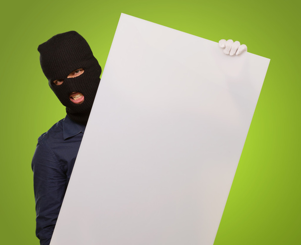 Homme portant un masque tenant une carte blanche sur un fond vert
 - Photo, image
