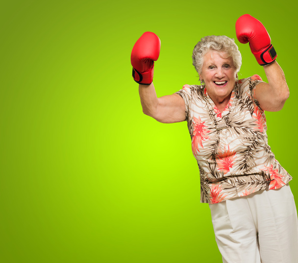 Happy Mature Woman Wearing Boxing Glove Cheering - 写真・画像